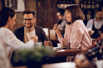 Happy friends talking while relaxing in a cafe.