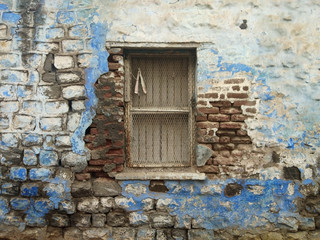Fototapeta na wymiar Vintage old window in an ancient cement and brick wall of an abandoned house. An outside window wall with paint peeling and damaged. 