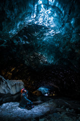 Female explorer standing inside ice cave tunnel, Iceland