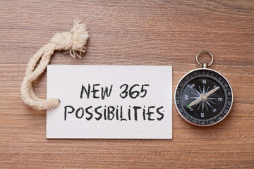 New 365 possibilities written on label with Compass on wood background