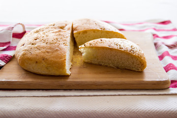 Fresh Focaccia bread with rosemary; Focaccia bread sliced on a wooden cutting board