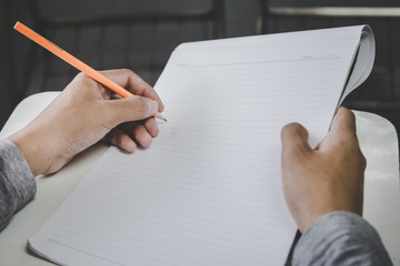 Fototapeta premium high school,university student study.hands holding pencil writing paper answer sheet.sitting lecture chair taking final exam attending in examination classroom.concept scholarship for education abroad