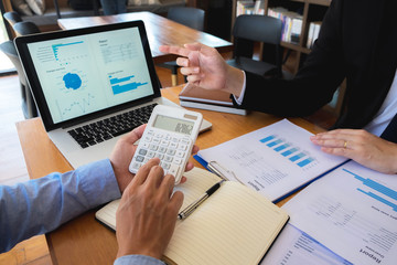 Sitting and working, consulting and suggesting work, checking work reports with a calculator in a...