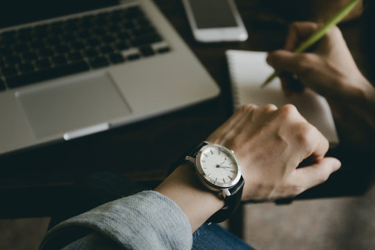 looking at luxury watch on hand check the time at workplace.concept for managing time organization working,punctuality,appointment.fashionable wearing stylish