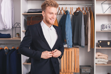 Handsome man trying on stylish clothes in dressing room