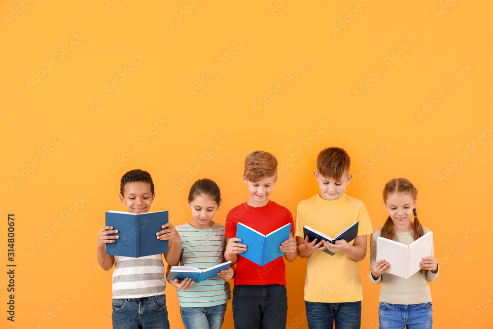 Wall mural Cute little children reading books on color background