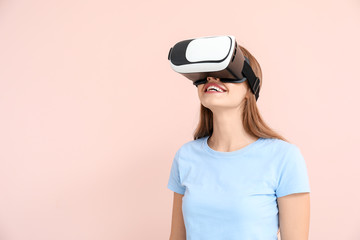 Young woman with virtual reality glasses on color background