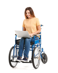 Obraz na płótnie Canvas Young woman in wheelchair and with laptop on white background