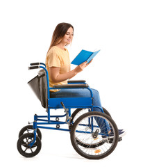 Young woman in wheelchair reading book on white background