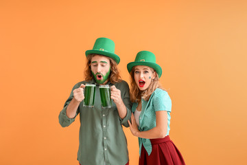 Young couple with beer on color background. St. Patrick's Day celebration