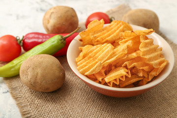 Plate with tasty potato chips on table