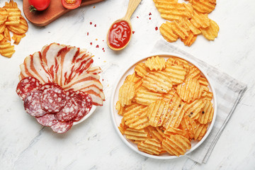 Composition with tasty potato chips and bacon on table