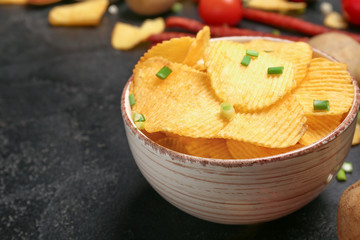 Bowl with tasty potato chips on table