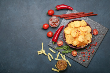 Composition with tasty potato chips on dark background
