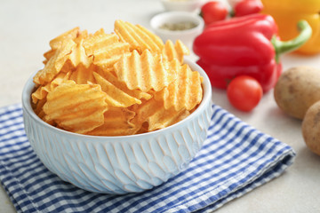 Bowl with tasty potato chips on table