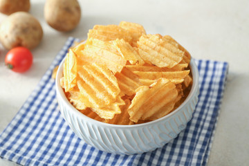 Bowl with tasty potato chips on table