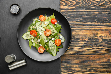 Plate with tasty salad on wooden background