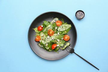 Plate with tasty salad on color background