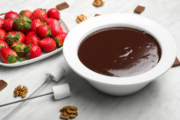 Bowl with tasty chocolate fondue, strawberry and marshmallow on table