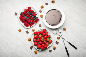 Bowl with tasty chocolate fondue, berries and marshmallow on table