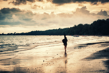 Naklejka premium woman wark on the beach at sunset