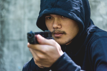 Robber with hood points the gun