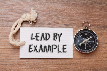 Lead by example - business tips handwriting on label with compass