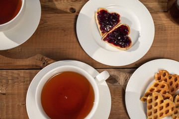 Heart shaped cookies with jam, a cup of tea, top view on rustic wood. Valentines Day