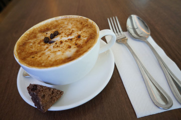 cup of coffee with cream on wooden background