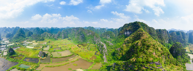 Fototapeta na wymiar Epic aerial view of Ninh Binh region, Trang An Tam Coc tourist attraction, UNESCO World Heritage Site, Scenic river crawling through karst mountain ranges in Vietnam, travel destination.