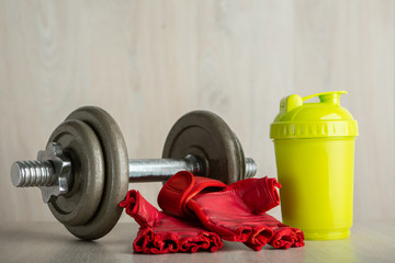 Iron dumbbell, Fitness Glove and Shaker on a wooden floor