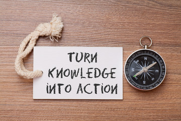 Turn knowledge into action -  Motivation advice handwriting on label with compass