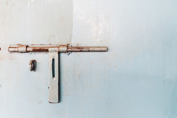 Close up of rusty steel door lock on an old blue meatal door.