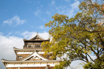 Facade of Hiroshima castle in autumn season against blue sky, called as Crab Castle, an ancient castle in Hiroshima, Japan. It was destroyed by atomic bombing and reconstructed later