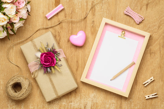 Mockup Blank photo frame for Valentines day concept. Top view of mock up photo frame with beautiful craft gift box decoration and rose flowers on grunge wood background.
