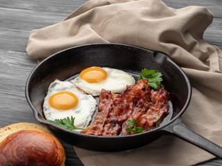 Fried eggs with bacon in a pan.