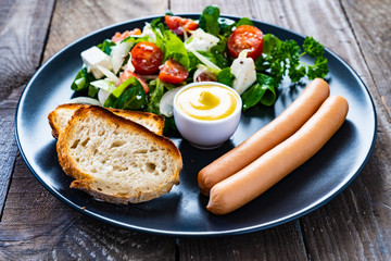 Fototapeta na wymiar Continental breakfast - boiled sausages, toasts and greek salad