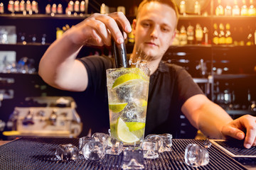 Bartender is making cocktail at bar counter. Fresh cocktails. Barman at work. Restaurant. Nightlife.