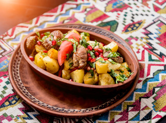 Fried potatoes with pieces of meat in a clay pot. European cuisine.