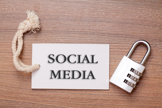 Combination number padlock on wood background with social media written on label tag