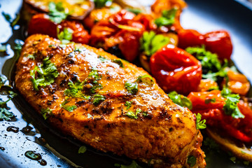 Roast chicken breast and vegetables on wooden background