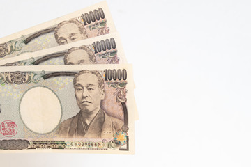 Stack of ten thousand Japanese Yen banknotes isolated on white background with copy space.