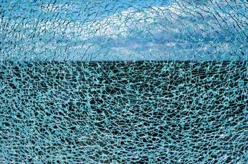 Cracked glass surface against blue sky