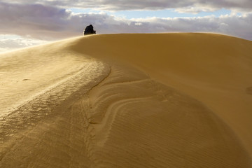 Fototapeta na wymiar Siwa Oasis, Egypt A man walks on the sand dunes outside the oasis.