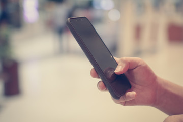 Close up of a man using mobile smart phone with blank copy space screen for your text message or information content, female reading text message on cell telephone during in urban setting