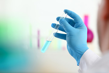 A male chemist holds test tube of glass in his hand overflows a liquid solution of potassium permanganate conducts an analysis reaction takes various versions of reagents using chemical manufacturing.