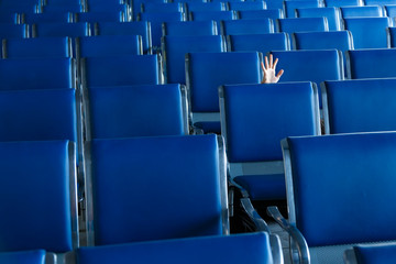 Row of blue seats and a human hand in airport hall