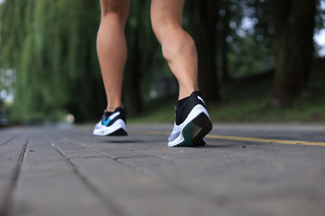 Fototapeta na wymiar Runner feet running on road closeup on shoe, outdoor at sunset or sunrise.