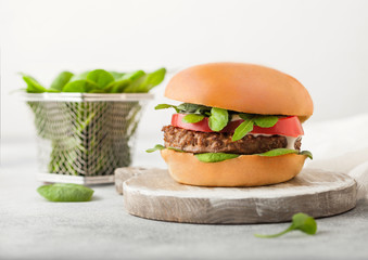 Healthy vegetarian meat free burger on round chopping board with vegetables and spinach on light...