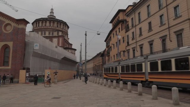 Tram and other traffic in a historical street in Milan, Italy, outside church with Da Vinci's Last Supper painting